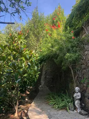 a garden with a statue next to a stone wall at Historic Villa In Sant Antonino With Sea Views in SantʼAntonino