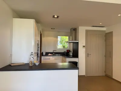 a kitchen with white cabinets and a black counter top at T4 Cote Plage N6 face a la mer in Pinarellu
