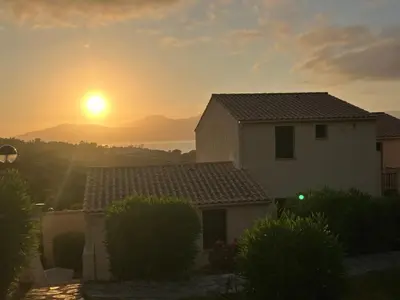 a house with the sunset in the background at La Petite Felicità - Jolie Vue sur la Baie d'Ajaccio in Grosseto-Prugna