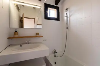 a white bathroom with a sink and a mirror at La Petite Felicità - Jolie Vue sur la Baie d'Ajaccio in Grosseto-Prugna