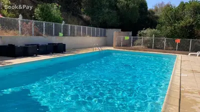 a swimming pool with blue water in a yard at La Petite Felicità - Jolie Vue sur la Baie d'Ajaccio in Grosseto-Prugna