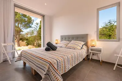 a bedroom with a bed and a large window at La Villa Pianottoli - Magnifique Vue Panoramique in Pianottoli-Caldarello