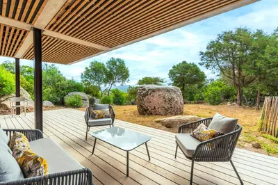 a wooden deck with chairs and a table at La Villa Pianottoli - Magnifique Vue Panoramique in Pianottoli-Caldarello