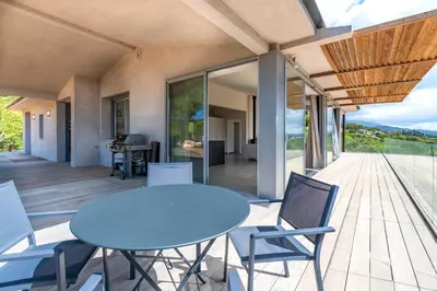 a patio with a table and chairs on a deck at La Villa Pianottoli - Magnifique Vue Panoramique in Pianottoli-Caldarello