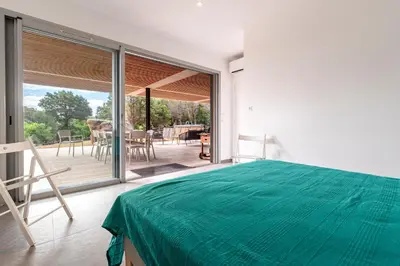 a bedroom with a green bed and a patio at La Villa Pianottoli - Magnifique Vue Panoramique in Pianottoli-Caldarello