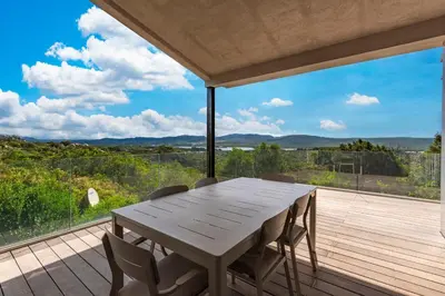 a wooden table and chairs on a deck with a view at La Villa Pianottoli - Magnifique Vue Panoramique in Pianottoli-Caldarello