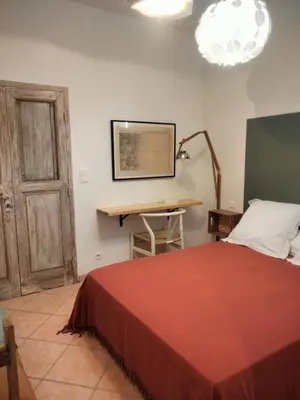 a bedroom with a bed and a desk and a lamp at La Maison De Stephanie in Porto-Vecchio