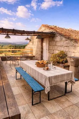 a patio with a table and chairs and a stone wall at La Maison De Stephanie in Porto-Vecchio