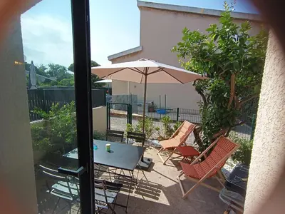 a patio with a table and chairs and an umbrella at Duplex Cosy- Sérénité en Bord de Mer in Borgo