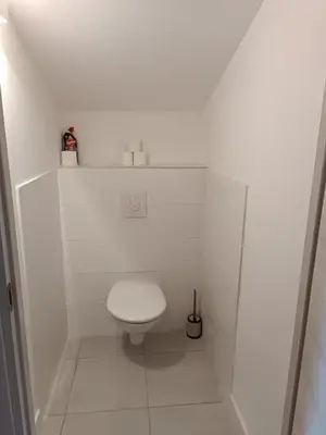 a white bathroom with a toilet in a stall at Duplex Cosy- Sérénité en Bord de Mer in Borgo