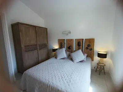 a bedroom with a large bed with a wooden headboard at Duplex Cosy- Sérénité en Bord de Mer in Borgo
