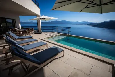 a group of chairs and a swimming pool with an umbrella at Villa d'architecte classée 5 étoiles in Campomoro