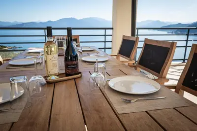 a wooden table with wine bottles and glasses on it at Villa d'architecte classée 5 étoiles in Campomoro