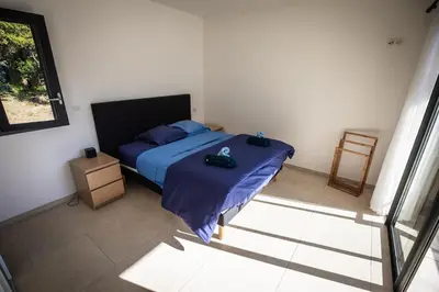 a bedroom with a bed with blue sheets and a chair at Villa d'architecte classée 5 étoiles in Campomoro