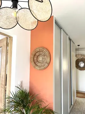 a hallway with an orange wall and two chandeliers at Casa Lucia in Aléria