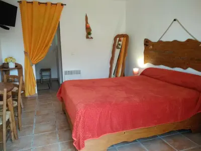 a bedroom with a red bed and a table at Chez Nat et JC in Eccica-Suarella