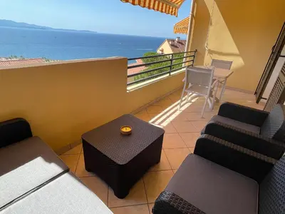 a balcony with chairs and a table and a view of the ocean at Le petit paradis avec vue mer in Ajaccio