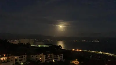 a full moon rising over the water at night at Le petit paradis avec vue mer in Ajaccio