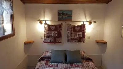 a bedroom with a bed with pillows on it at Beau logement de type F3 avec jardin fleuri à 5 min de la plage in Cargèse