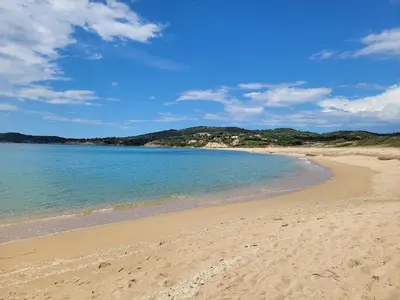 a beach with the ocean and mountains in the background at Beau logement de type F3 avec jardin fleuri à 5 min de la plage in Cargèse