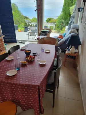a table with glasses and plates on it on a balcony at Beau logement de type F3 avec jardin fleuri à 5 min de la plage in Cargèse
