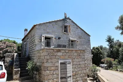 an old stone building with a balcony on a street at Casa di Lilla - Escapade dans une maison de charme in San-Gavino-di-Carbini