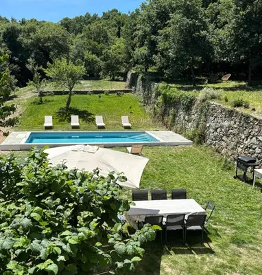 a pool with a table and chairs in the grass at La demeure des vignes in Murato
