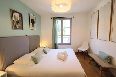 a bedroom with a white bed and a window at Le Nathalia - T3 4 étoiles, vue port de Bonifacio in Bonifacio