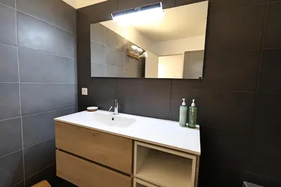 a bathroom with a sink and a mirror at Le Nathalia - T3 4 étoiles, vue port de Bonifacio in Bonifacio
