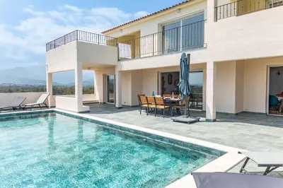 a swimming pool with chairs and a table next to a pool at Villa Vista Di Pinarello in Pinarellu