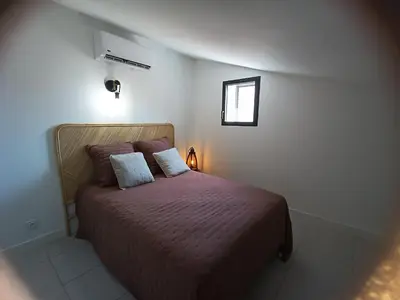 a bedroom with a bed with purple sheets and a window at havre de paix au bord de mer - Casa Marina in Borgo