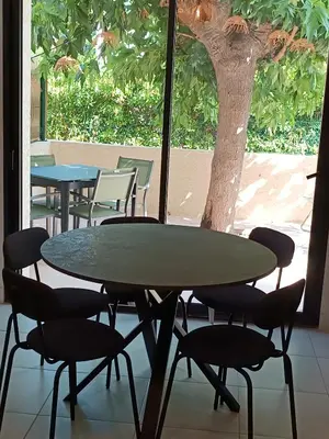 a table and chairs in a room with a tree at havre de paix au bord de mer - Casa Marina in Borgo