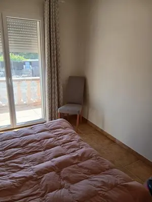 a bedroom with a bed and a chair and a window at Chez Rachel chambre et salle bain privative chez l'habitant in Aléria