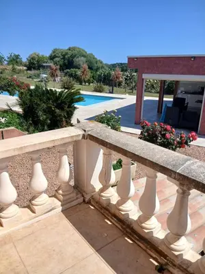 a stone fence with flowers and a pool at Chez Rachel chambre et salle bain privative chez l'habitant in Aléria