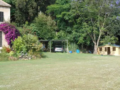 a yard with a car parked in a garden at B&B la rivière in Penta-di-Casinca