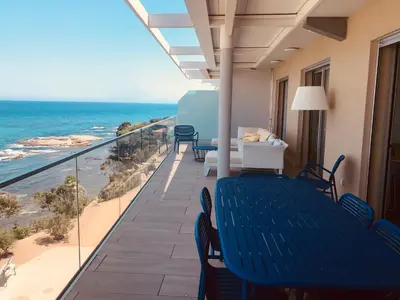 a balcony with a blue table and chairs and the ocean at Haut standing- Face à la mer! 3 chambres-piscine semi olympique in Sari Solenzara