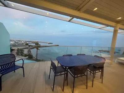a table and chairs on a balcony with a view of the ocean at Haut standing- Face à la mer! 3 chambres-piscine semi olympique in Sari Solenzara