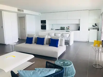 a living room with a white couch and blue pillows at Haut standing- Face à la mer! 3 chambres-piscine semi olympique in Sari Solenzara