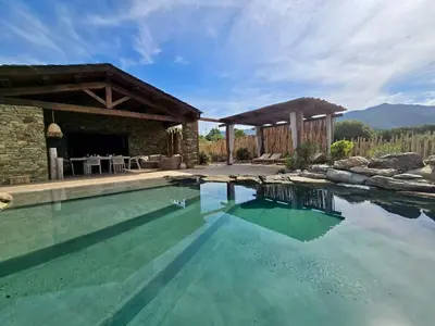 a swimming pool with a patio and a house at U Loghju in Oletta