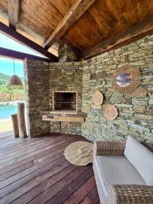 an outdoor living room with a stone fireplace at U Loghju in Oletta