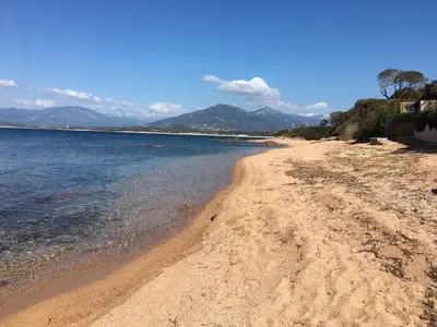 a sandy beach with water and mountains in the background at Maisonnette 2 minutes pied plage in Grosseto-Prugna