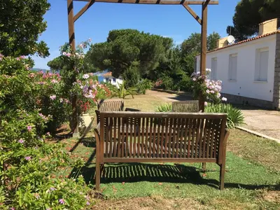 a wooden bench sitting in a garden with flowers at Maisonnette 2 minutes pied plage in Grosseto-Prugna