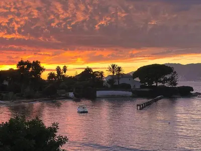 a boat in a body of water with a sunset at Maisonnette 2 minutes pied plage in Grosseto-Prugna