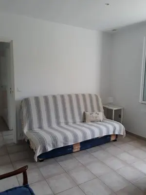 a couch sitting in a room with a white wall at Maisonnette 2 minutes pied plage in Grosseto-Prugna
