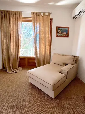 a bedroom with a bed and a chair and a mirror at Villa Paomia in Cargèse