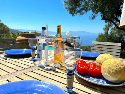 a wooden table with an umbrella and chairs at Villa Paomia in Cargèse
