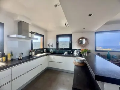 a large kitchen with white cabinets and a large window at Villa d'exception à Tizzano in Sartène