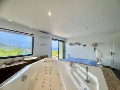 a large white bath tub in a room with a bed at Villa d'exception à Tizzano in Sartène