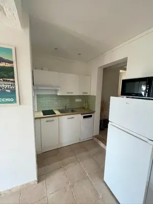 a kitchen with white cabinets and a white refrigerator at Dolce Corsica in Porto-Vecchio
