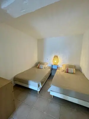 two beds in a small room with a lamp at Dolce Corsica in Porto-Vecchio